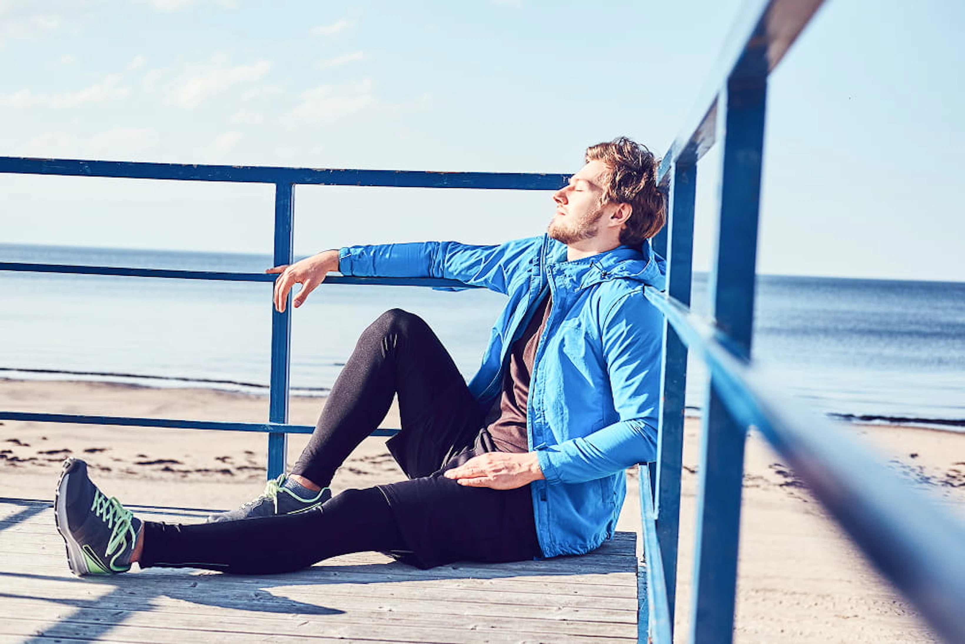 sportive young man is chilling near sea while sitting balcony bright sunny day 1