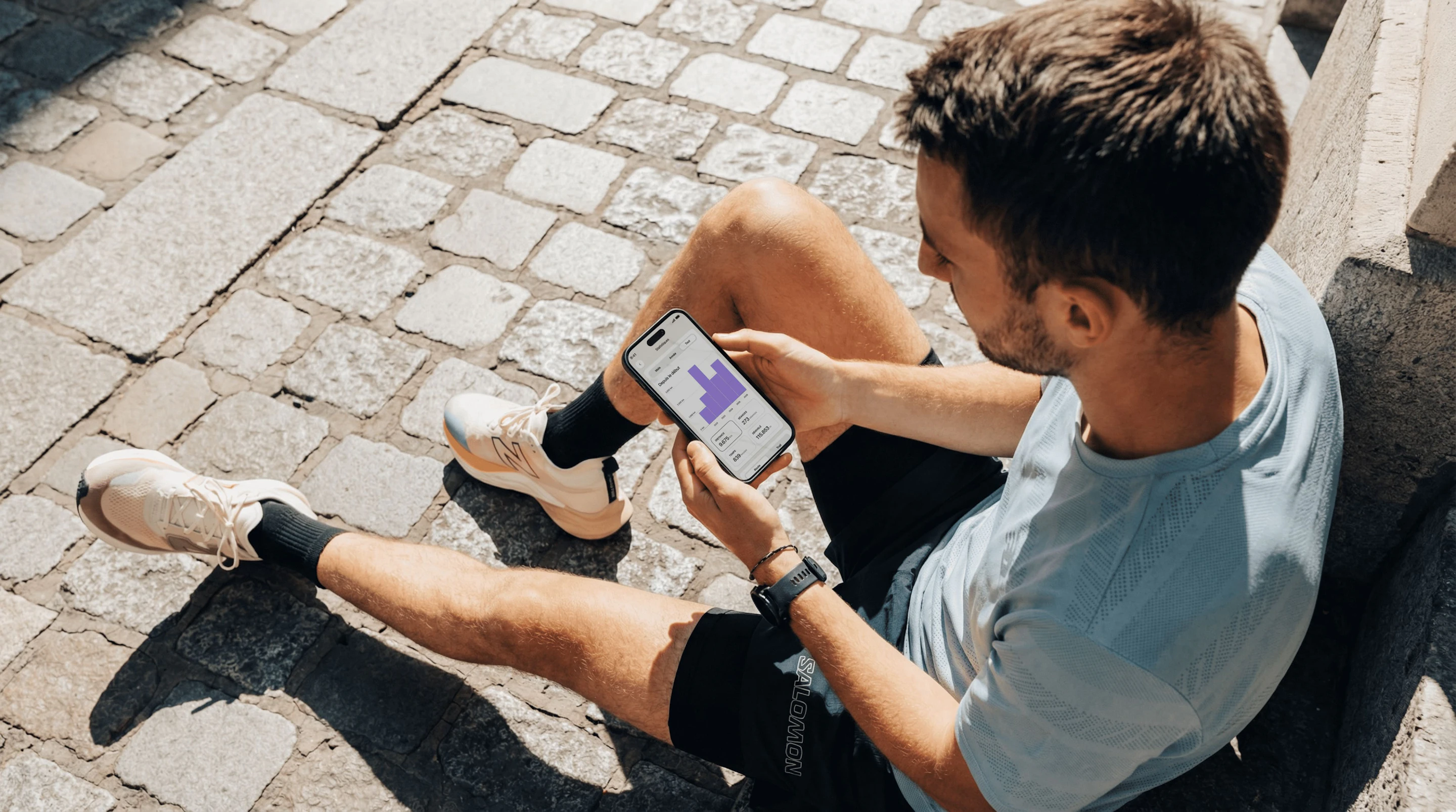 Coureur assis en train de consulter ses statistiques sur l'application Campus Coach