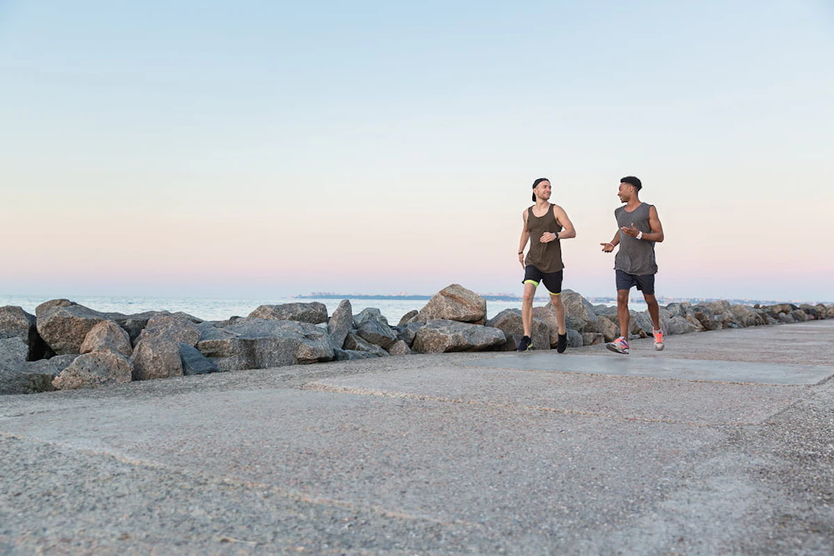 deux hommes courent en discutant au bord de la mer