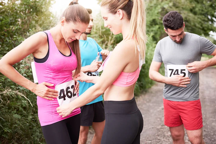 une femme accroche le dossard d'une autre sur le ventre tandis qu'un homme accroche le sien