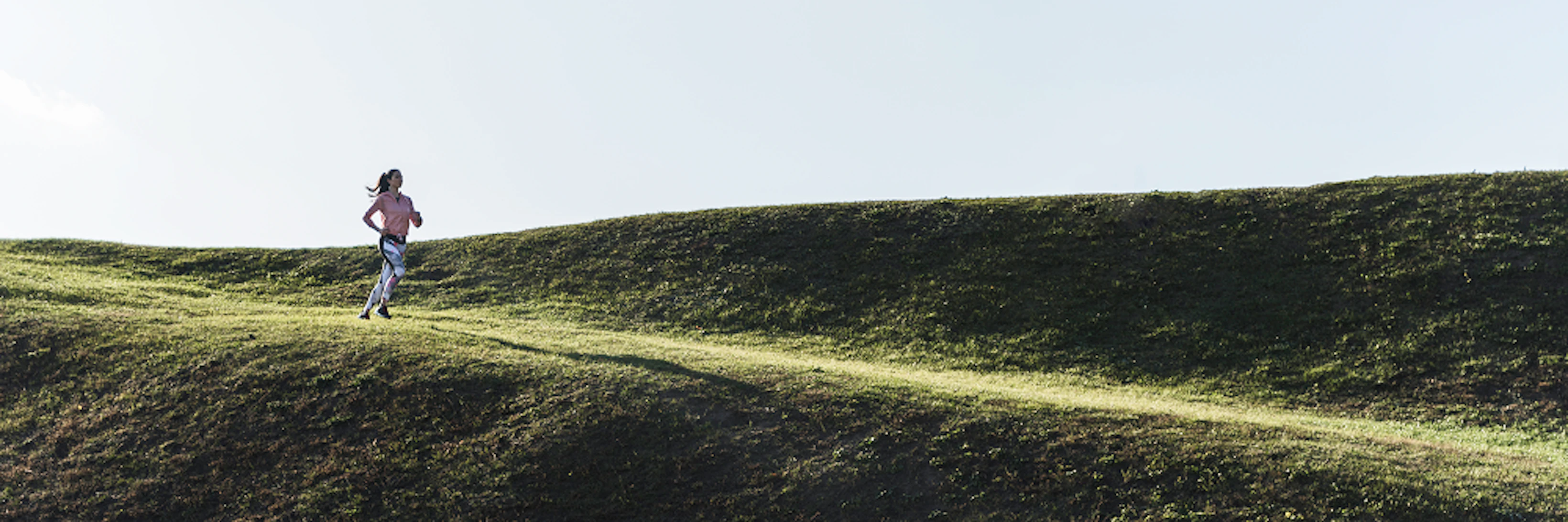 femme court sur une colline verdoyante