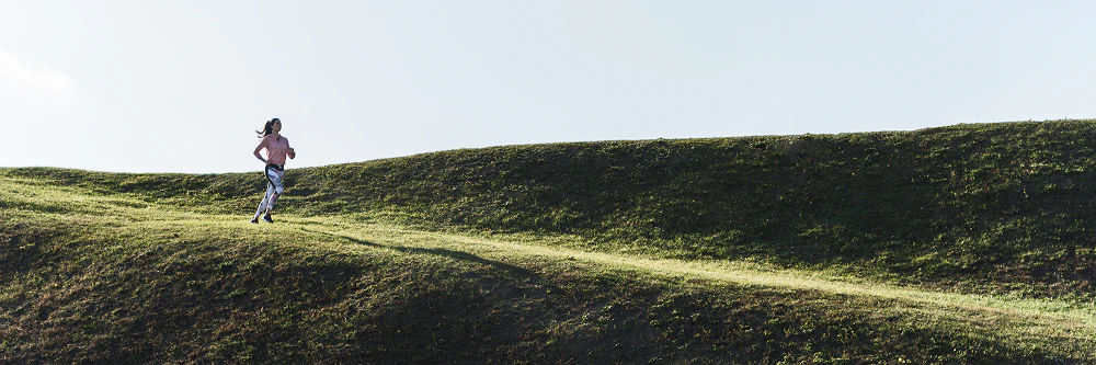 femme court sur une colline verdoyante