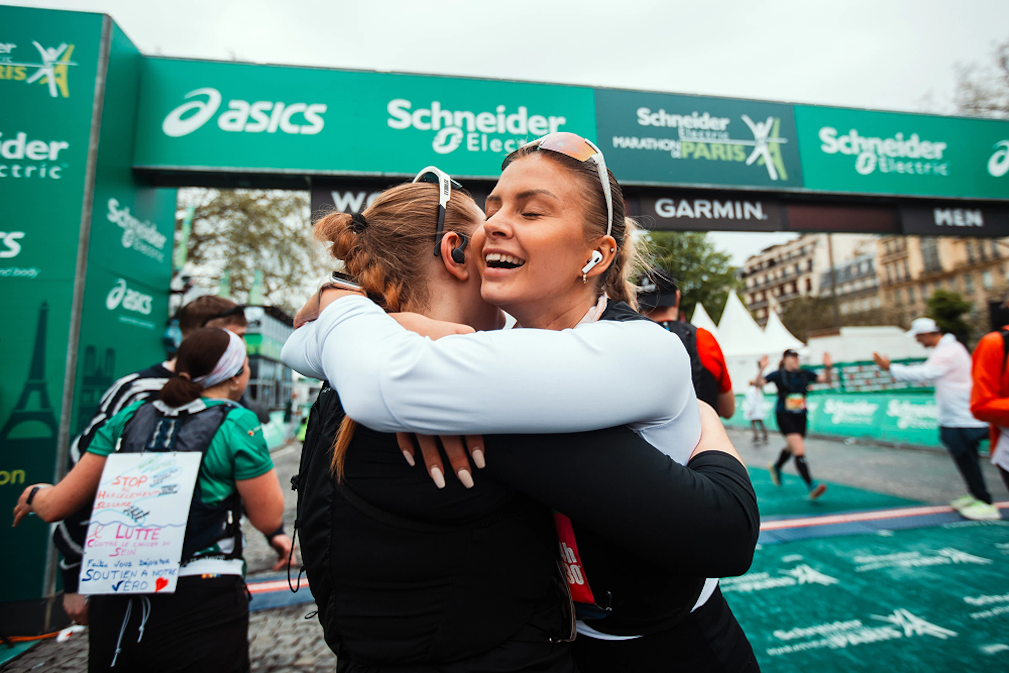 Deux coureuses s'enlacent après avoir franchi la ligne d'arrivée du marathon de Paris