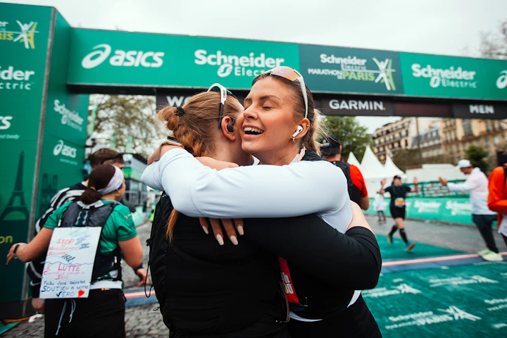 Deux coureuses s'enlacent après avoir franchi la ligne d'arrivée du marathon de Paris