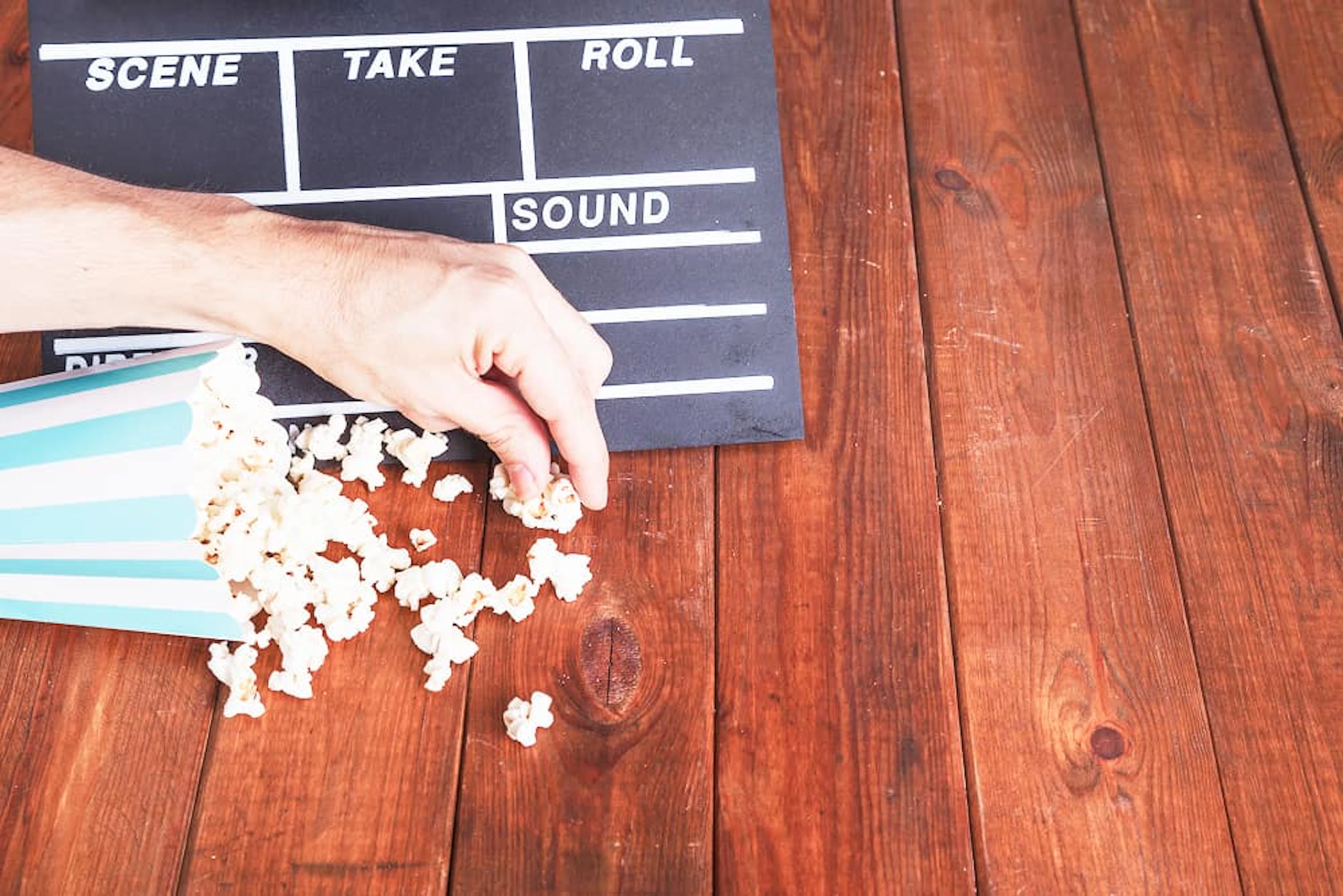 main attrape du pop corn devant un clap de film