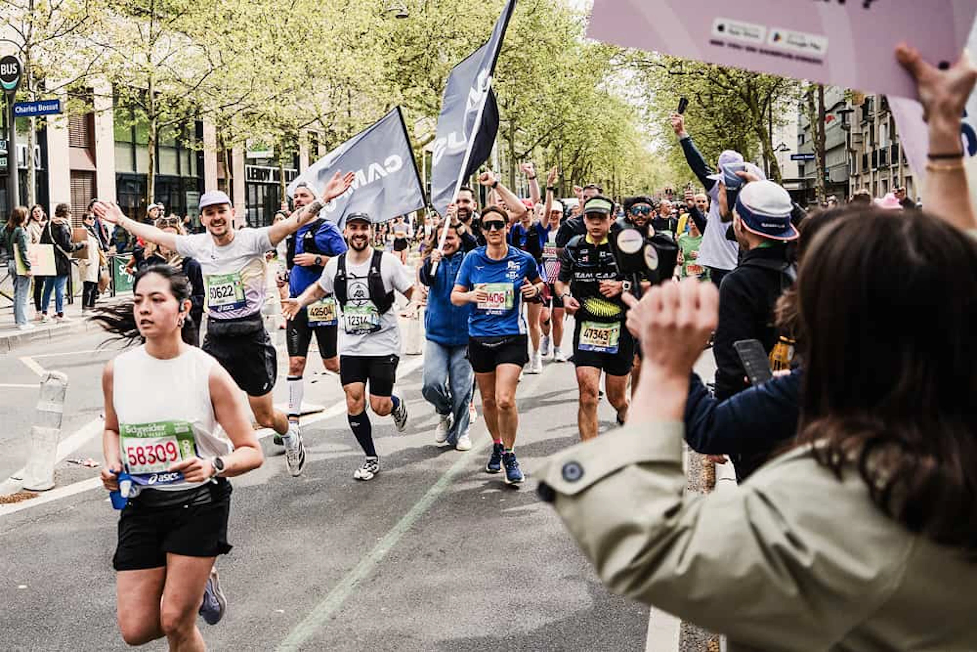 des coureurs courent un marathon avec un drapeau et des gens les encouragent