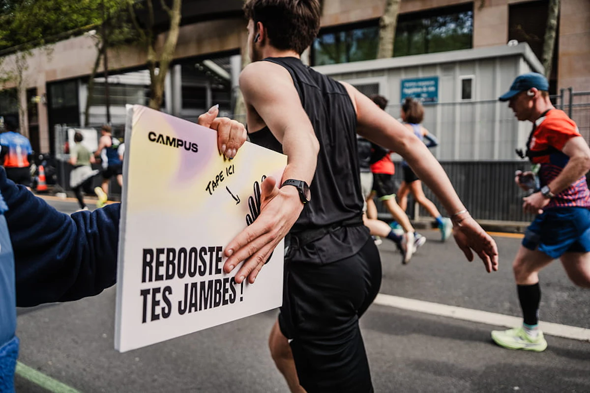 un coureur tape dans une pancarte d'encouragement avec sa main