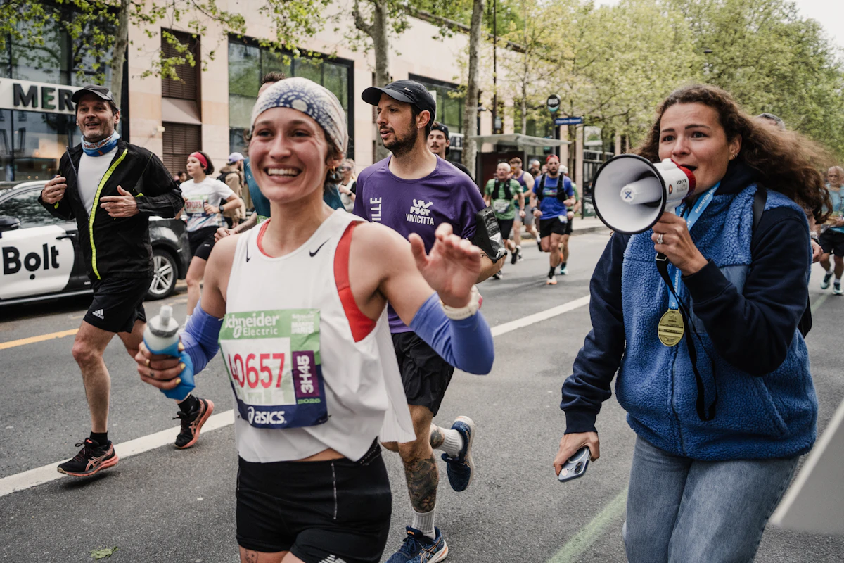 une femme court le marathon de paris 2026 et une autre la suit avec un gigaphone