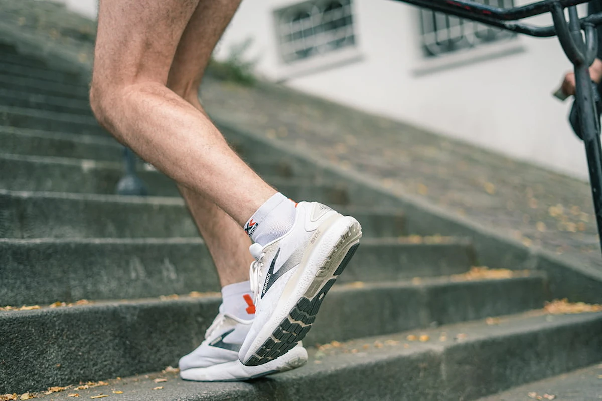 Un homme portant une paire de chaussures blanches monte des escaliers.