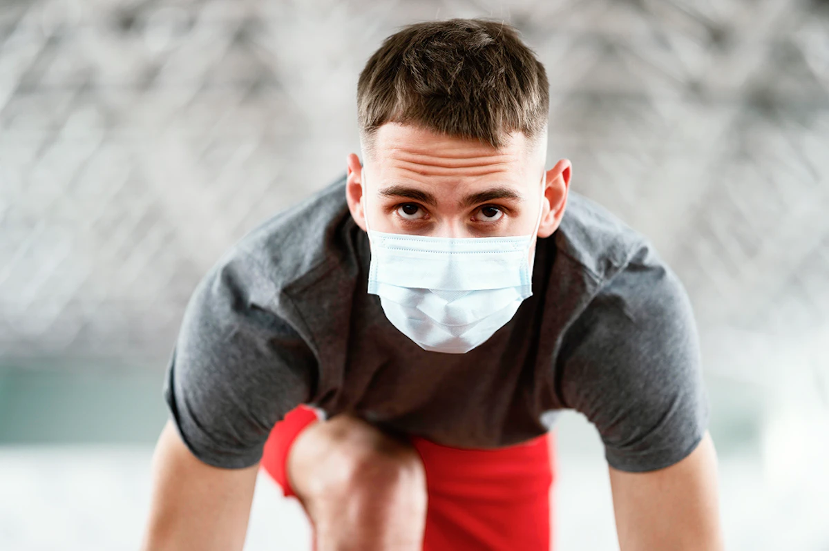 Athlète en position starting blocks qui porte un masque chirurgical