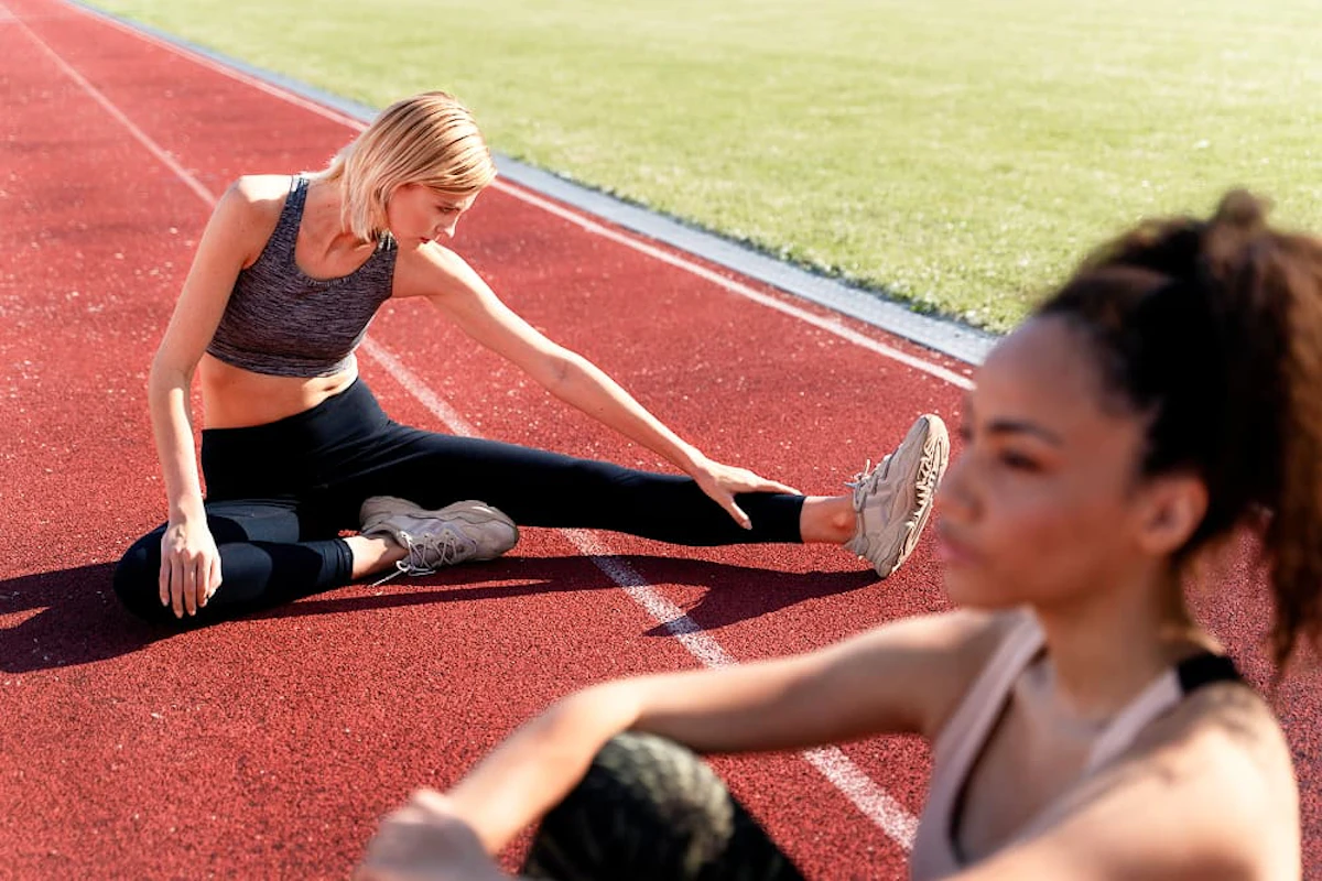 Deux femmes s'étirent sur une piste d'athlétisme