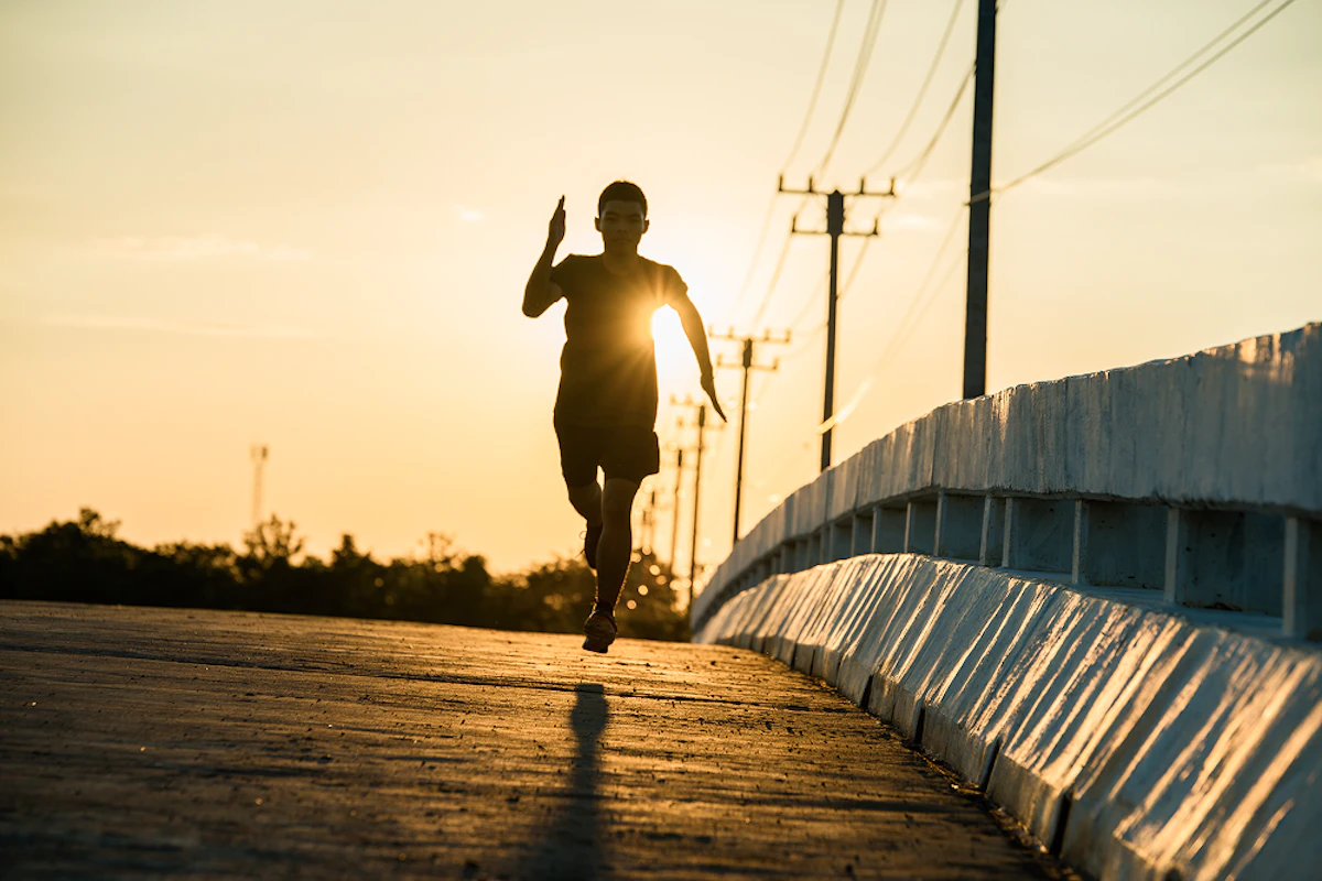 Un homme en contre-jour court sur une route