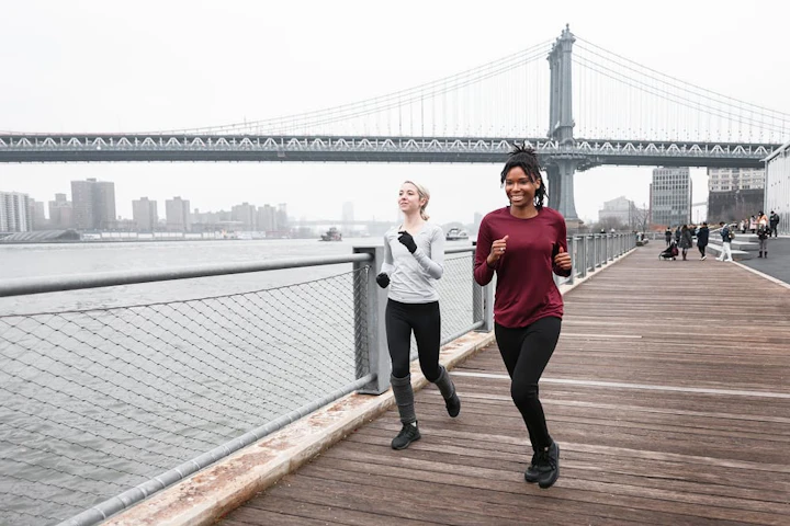 deux femmes courent sur une promenade sous un pont en fer