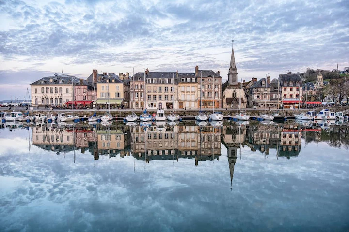 port de honfleur en Normandie avec des bateaux et des bâtiments qui se reflètent sur l'eau