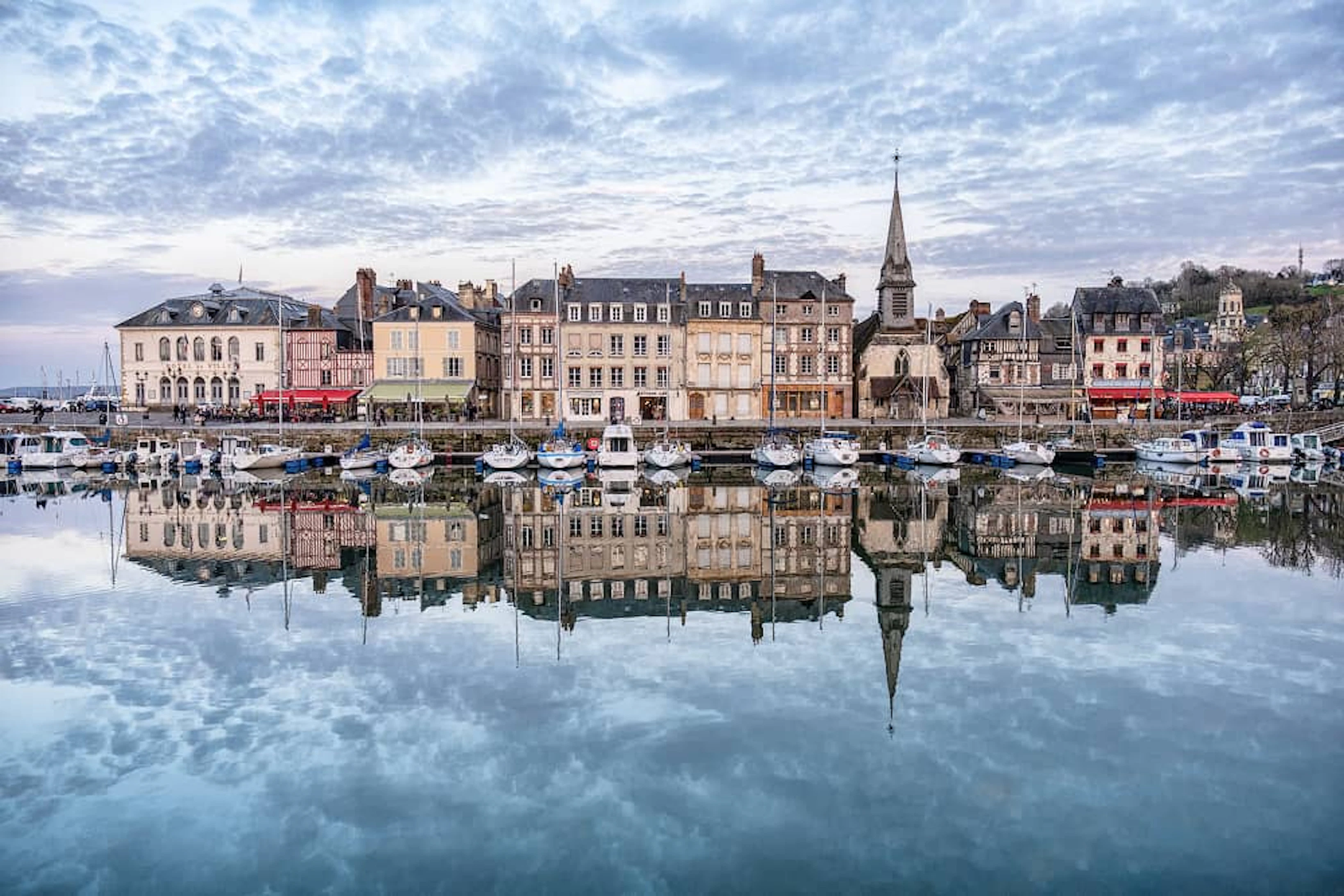port de honfleur en Normandie avec des bateaux et des bâtiments qui se reflètent sur l'eau