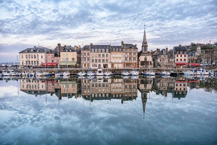 port de honfleur en Normandie avec des bateaux et des bâtiments qui se reflètent sur l'eau