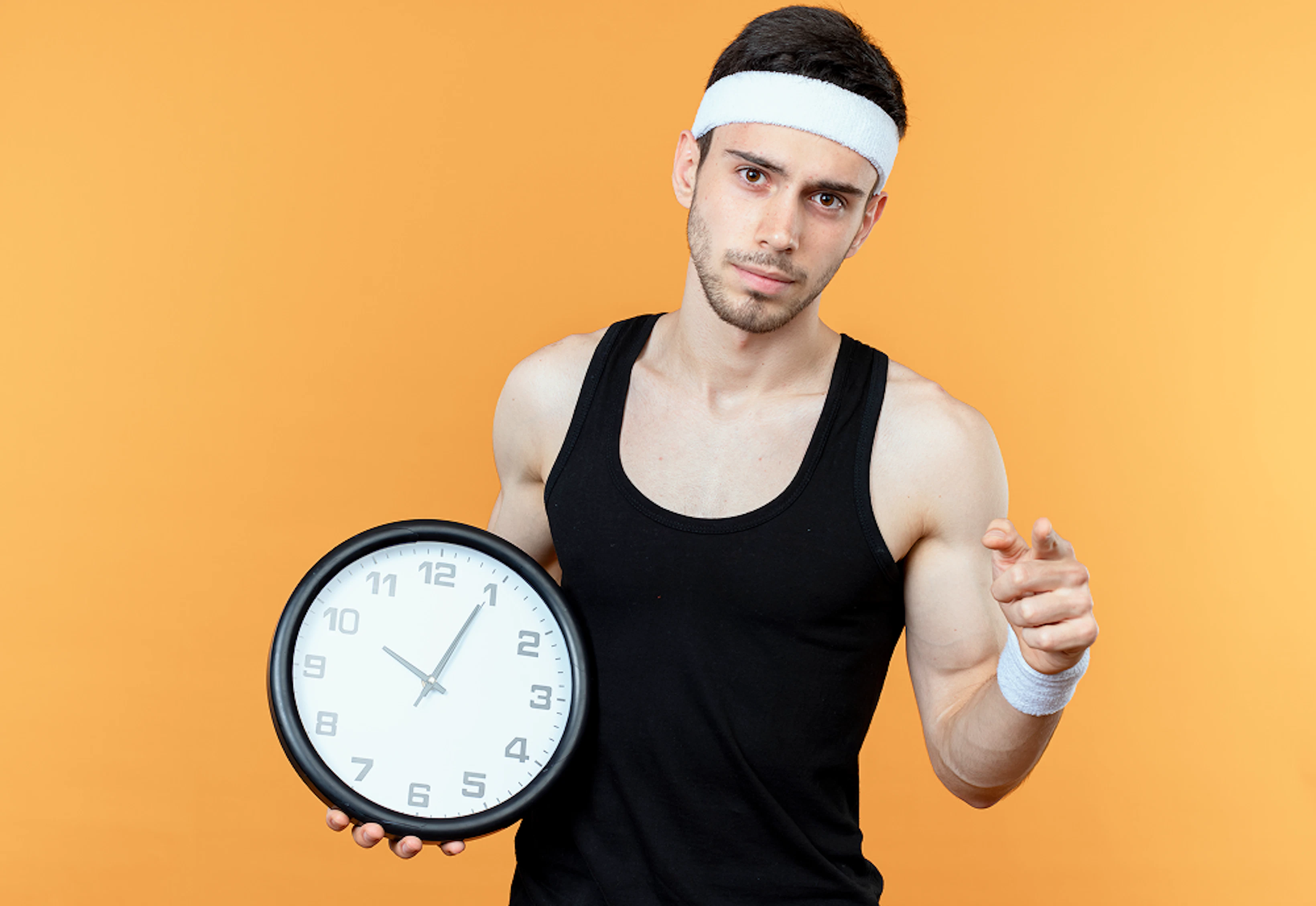 un homme en débardeur noir avec un bandeau blanc tient une horloge avec un fond orange à l'arrière
