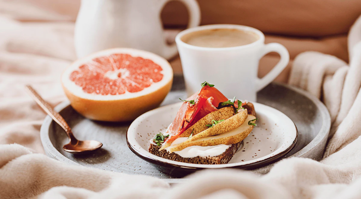 Petit-déjeuner riche en protéines : café, pamplemousse, pain, fromage blanc, charcuterie.