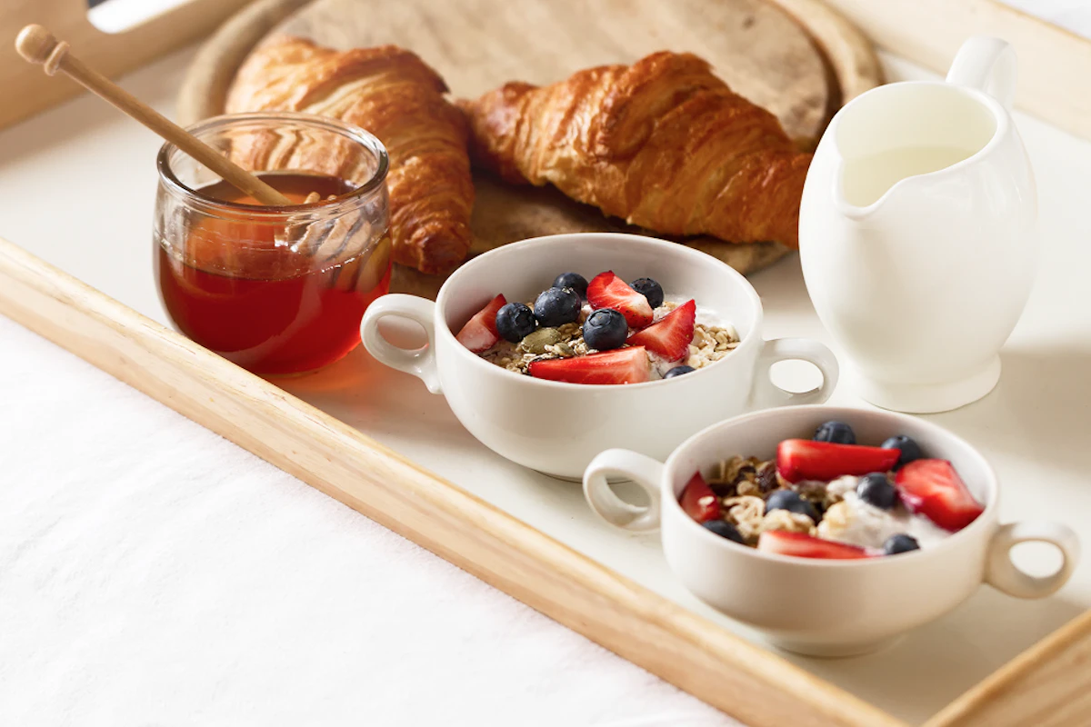 Protéines le matin : fromage blanc, fruits rouges, flocons d'avoine, miel, croissant, lait.