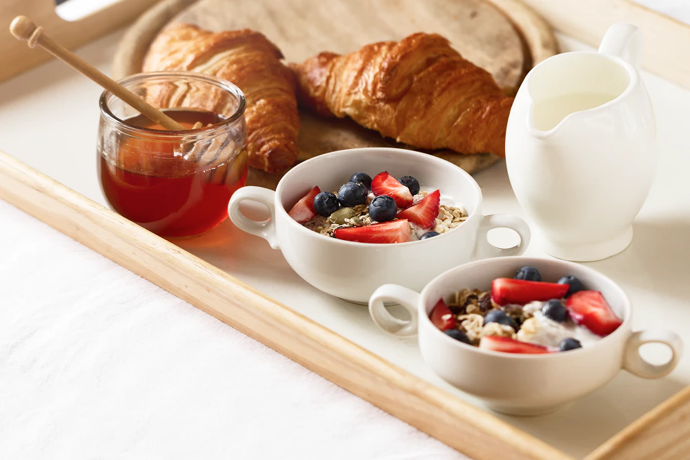 Protéines le matin : fromage blanc, fruits rouges, flocons d'avoine, miel, croissant, lait.