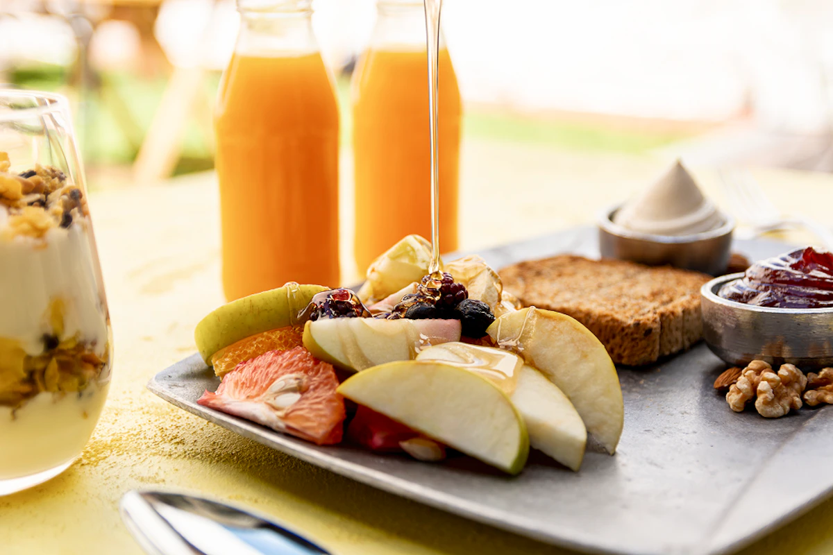Petit-déjeuner protéiné : fruits, miel, muesli, yaourt, pain, oléagineux, jus d'orange, etc.