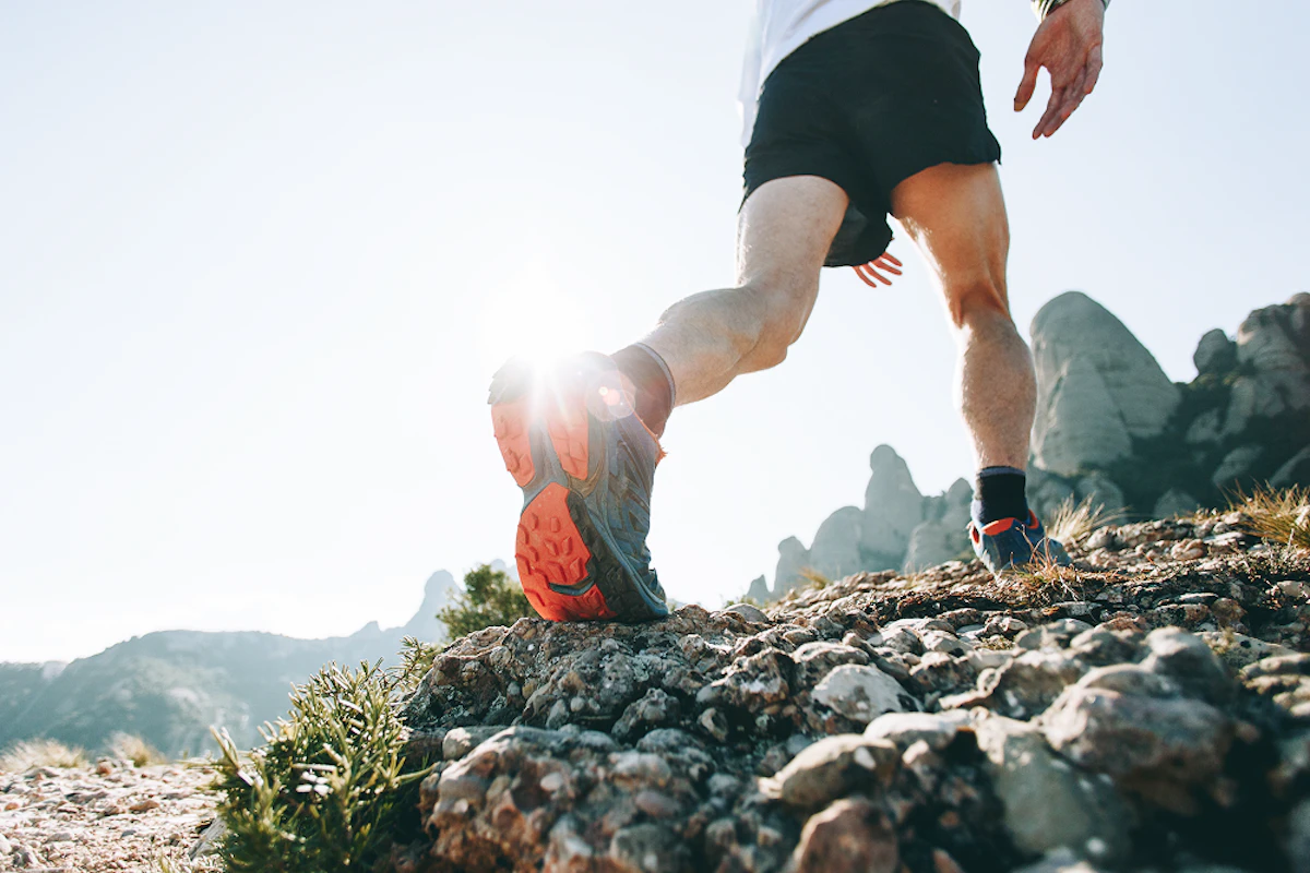 Un homme fait du trail running dans un paysage montagneux.