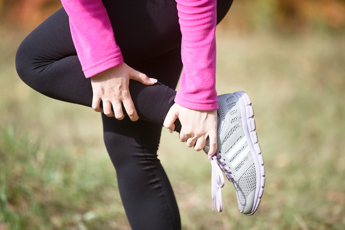 Une femme se maintient la jambe.