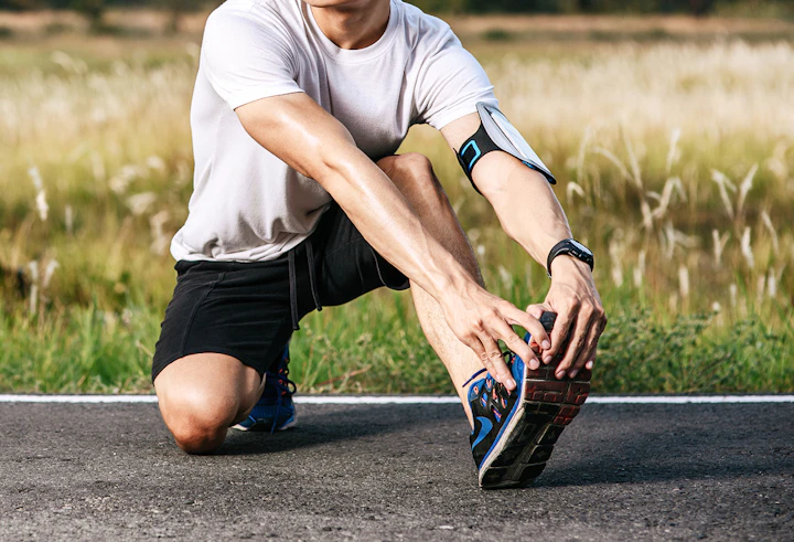 Un homme en tenue de course à pied se tient l'avant du pied.