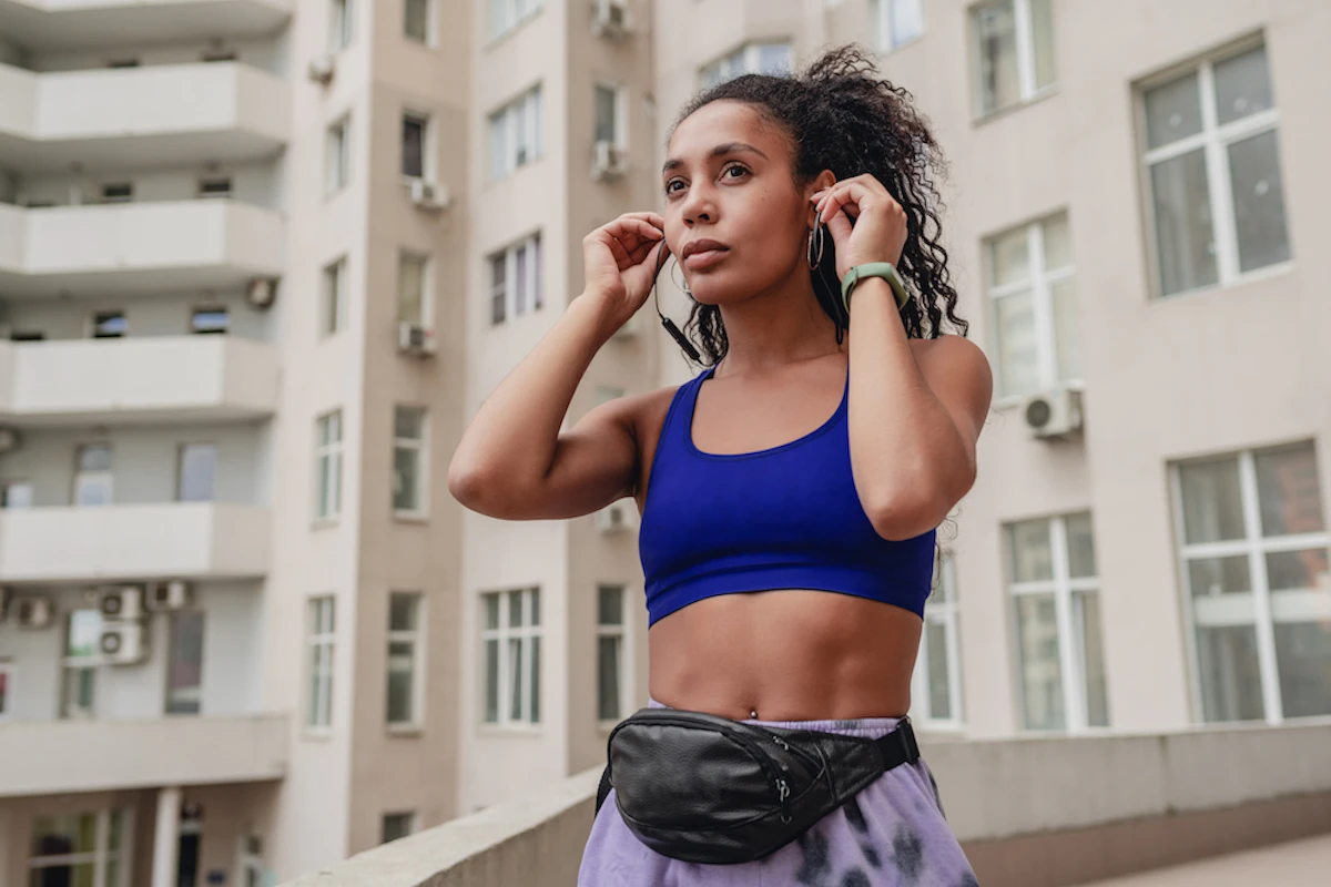 Une femme en brassière de running enfile ses écouteurs.