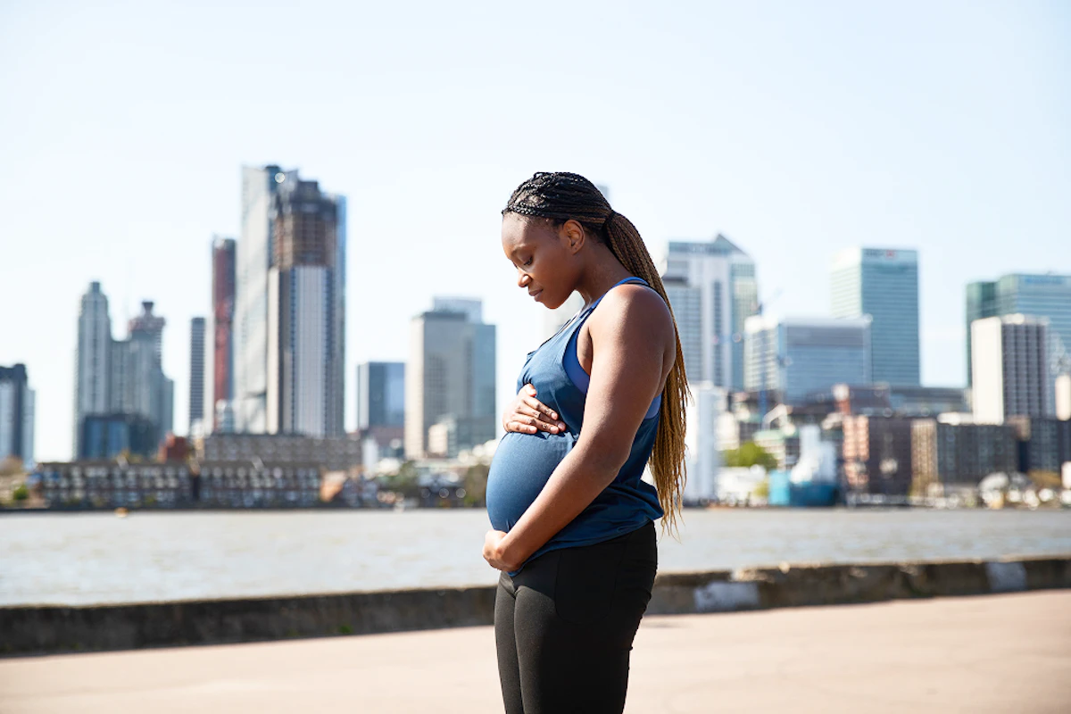 Une femme enceinte en tenue de running se tient le ventre