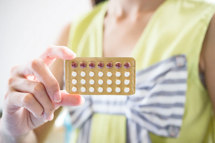 Une femme tient une plaquette de pilules contraceptives dans sa main.