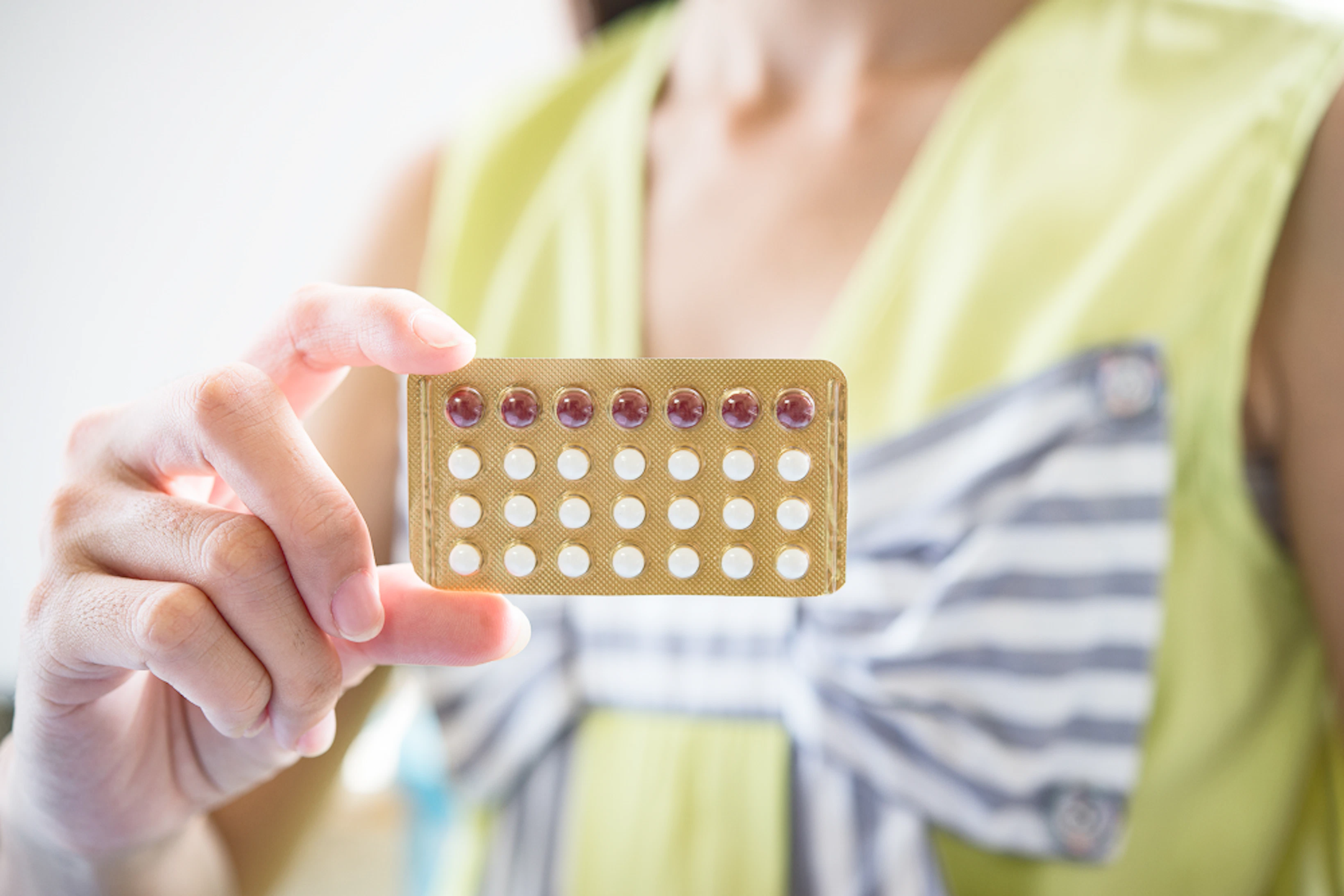 Une femme tient une plaquette de pilules contraceptives dans sa main.