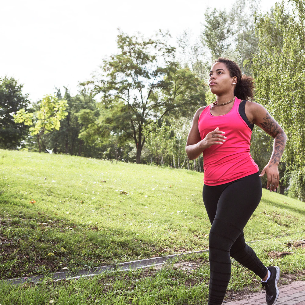 Une femme en tenue de sport court dans un parc.