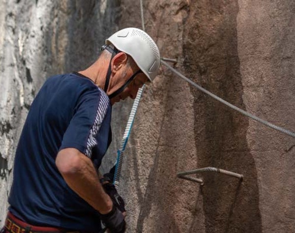 Senior via ferrata climbing Senior climbing via ferrata in the mountains — activity accessible for adults