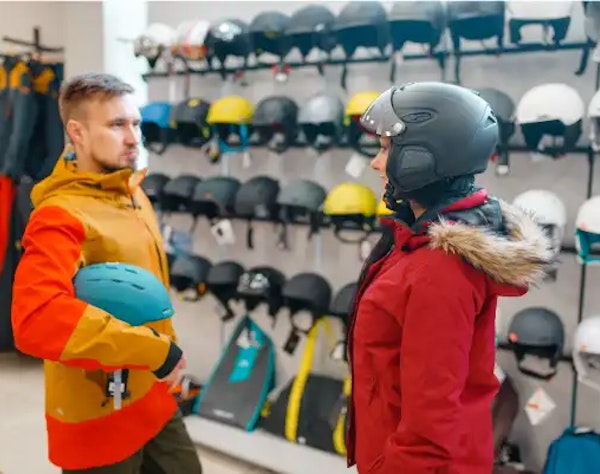 Choosing a ski helmet Adults trying ski helmets in a sports shop — safety gear for slopes