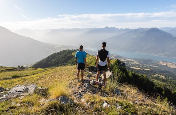 Trail à Réallon avec vue panoramique sur le lac de Serre-Ponçon Deux traileurs sur une crête de Réallon face au panorama montagnard du lac de Serre-Ponçon