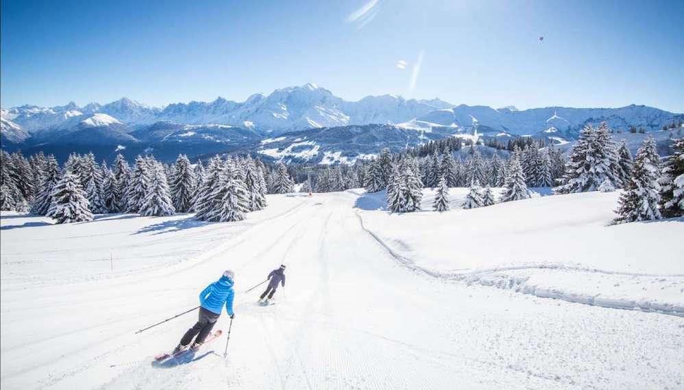 Skieurs sur une large piste de Combloux face à la chaîne du Mont-Blanc