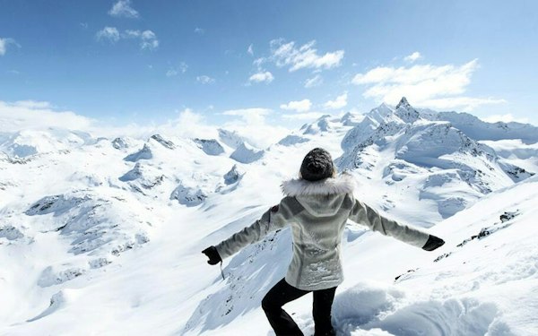 Skieuse bras ouverts face au panorama des sommets enneigés de Courchevel en Savoie