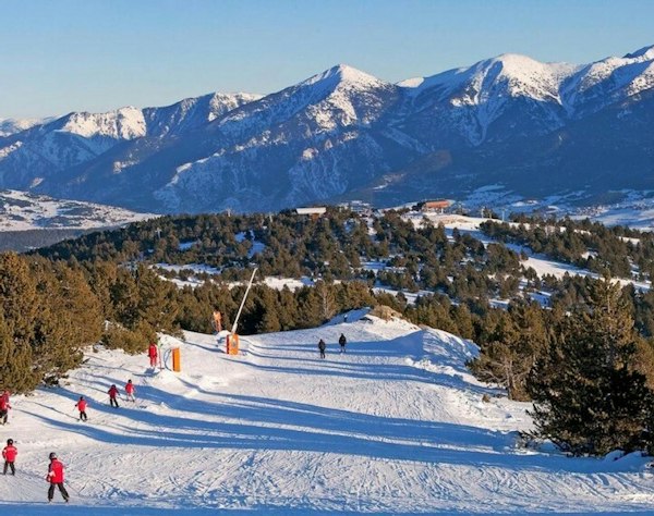 Forfait ski Font-Romeu Pyrénées 2000 pas cher | Passe Montagne Skieurs sur les pistes boisées de Font-Romeu face aux sommets des Pyrénées
