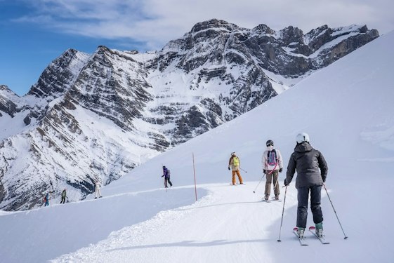 Forfait ski Gavarnie pas cher | Passe Montagne Skieurs face aux parois rocheuses du cirque de Gavarnie dans les Hautes-Pyrénées