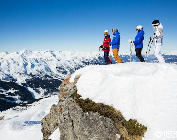 Forfait ski Méribel pas cher | Passe Montagne Groupe de skieurs au sommet d’un rocher de Méribel face au panorama de Savoie
