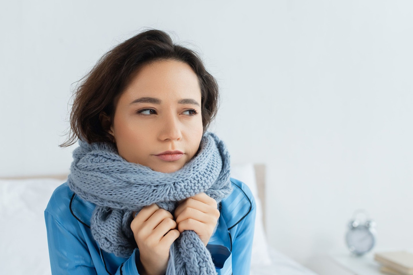 Halsweh: Hals warm halten Frau mit Schal im Bett