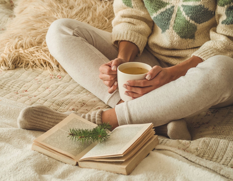 Frau mit Tasse Tee vor einem Buch