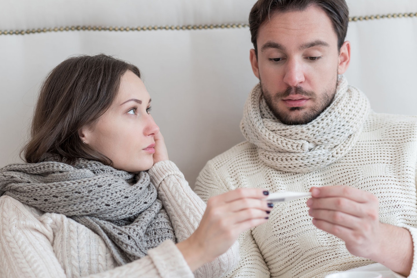 Erkältetes Paar im Bett mit Fieberthermometer