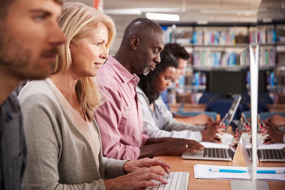 verschiedene Menschen in einer Bibliothek am Rechner oder Laptop