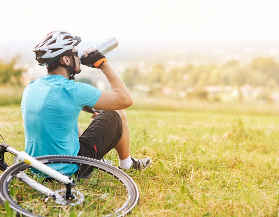 Gesunde Lebensweise Mann mit Velo bei der Rast auf einer Wiese