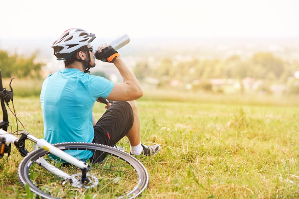 Mann mit Velo bei der Rast auf einer Wiese