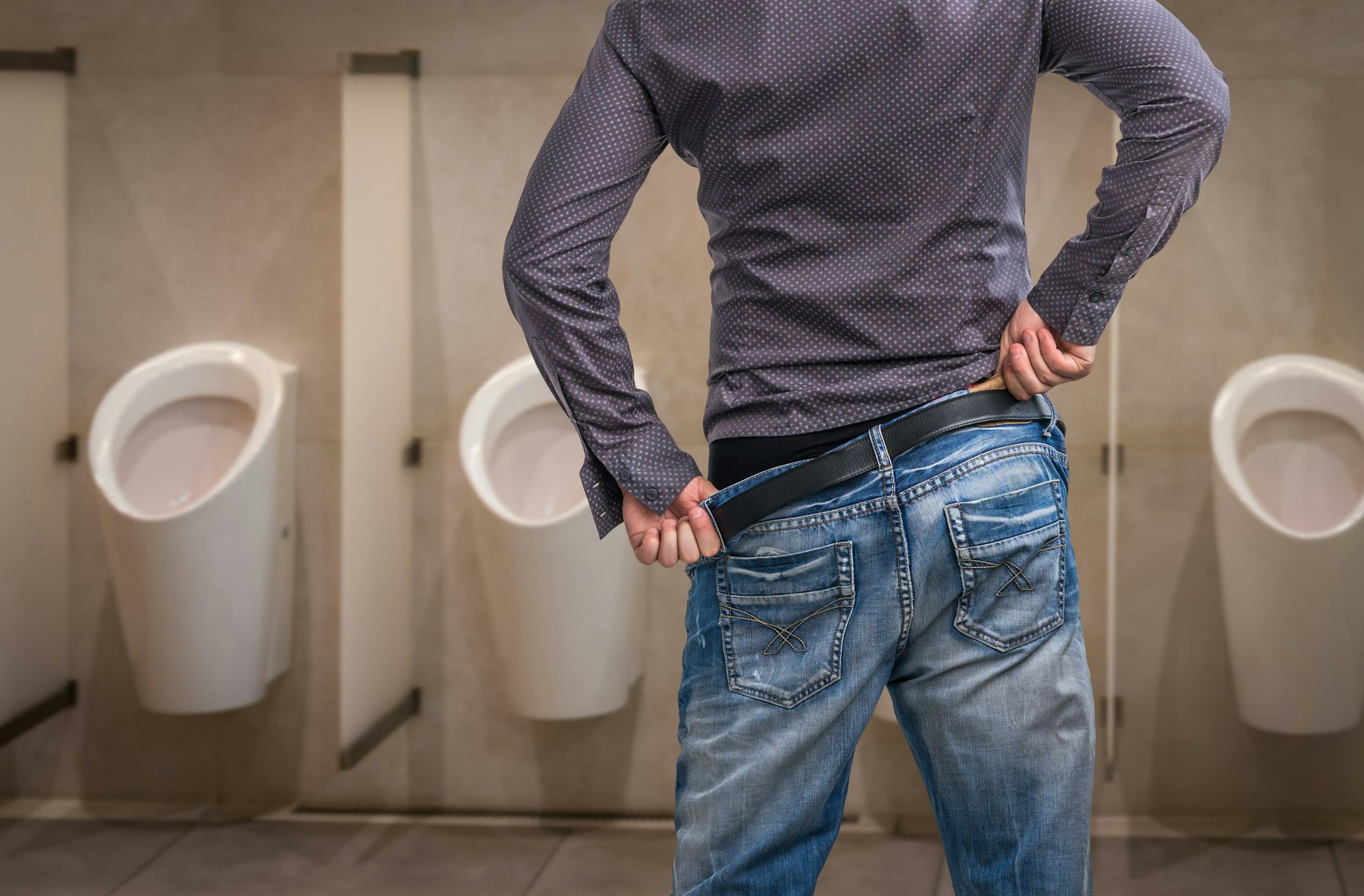 Harndrang Mann vor dem Pissoir