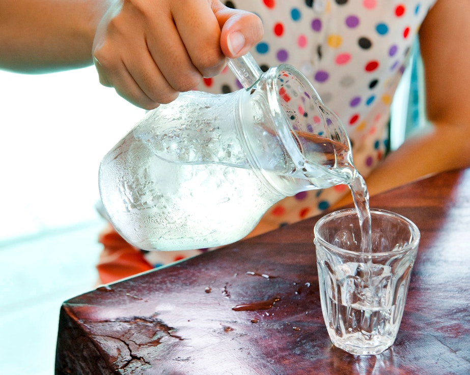 Frau schenkt Wasser aus Krug ein