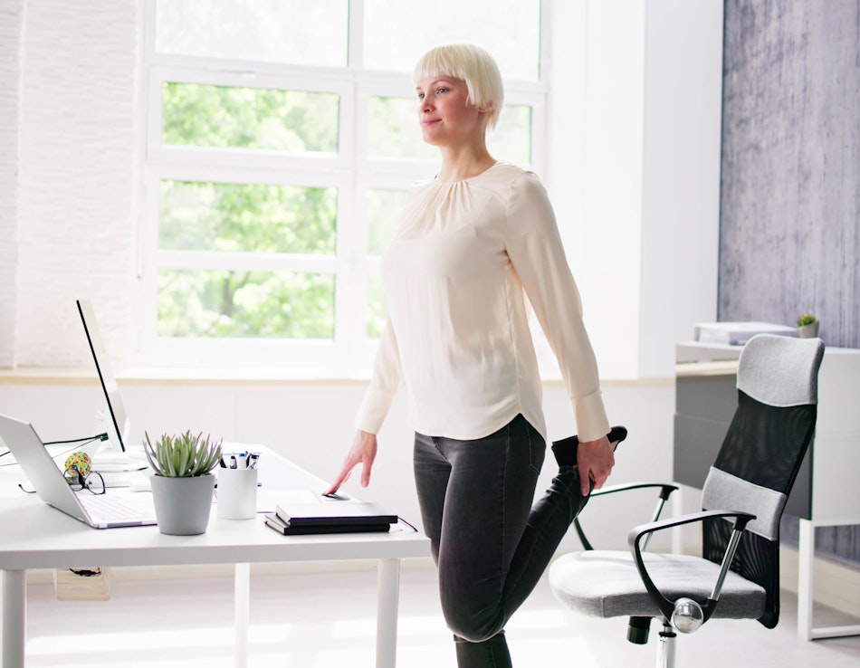 Bewegung, auch im Büro Frau macht Dehnungsübungen im Büro